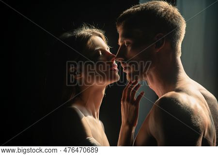 Beautiful Loving Couple Posing On Dark Backgroung With Night Lights. Man Embracing And Going To Kiss