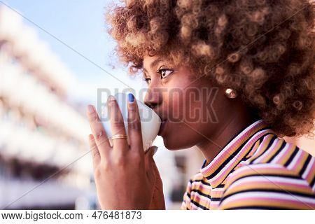 Young African Woman Drinking Tea In Her Balcony In The Morning Enjoying The Day And Feeling Relaxed.