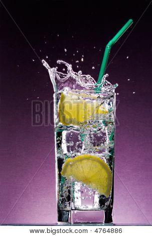 アイス キューブと緑のわらのアルコール飲料のガラスのテクスチャのすみれ色 B に落下レモン スライス
