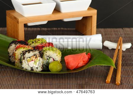 Velsmagende Maki sushi - Roll på grønne blade på bordet på grå baggrund