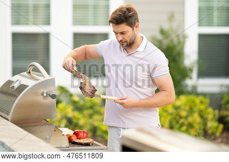 Barbecue Master. Middle Aged Hispanic Man In Apron For Barbecue. Roasting And Grilling. Man Hold Coo