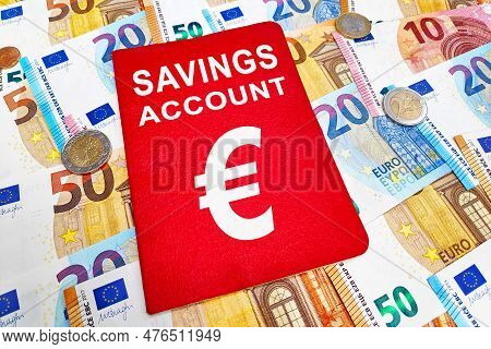Savings Account Passbook Atop Of A Stack Of Euro Banknotes And Coins.