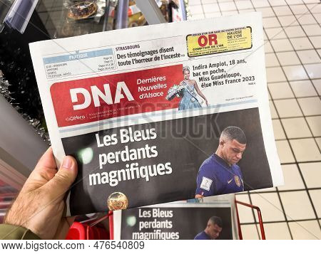Paris, France - Dec 19, 2022: Pov Male Hand Holding Dna Dernieres Nouvelles Dalsace Newspaper With H