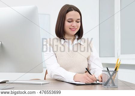 Happy Young Intern Working At Table In Modern Office