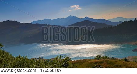 Lake Of Roselend And Blue Turquoise Water Borded By Range Mountains At Sunset In French Alps