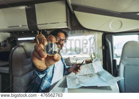 Travel And Adventure People Lifestyle. One Man Portrait Showing Compass And Using Road Map Paper To 