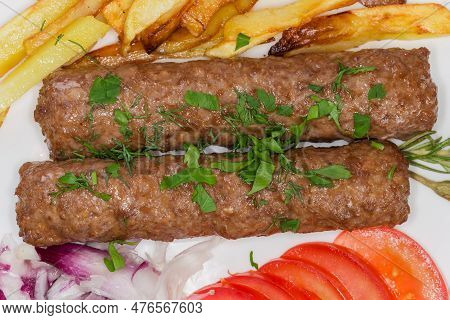 Two Baked Lula Kebab With French Fries And Chopped Vegetables On The Dish, Top View Close-up