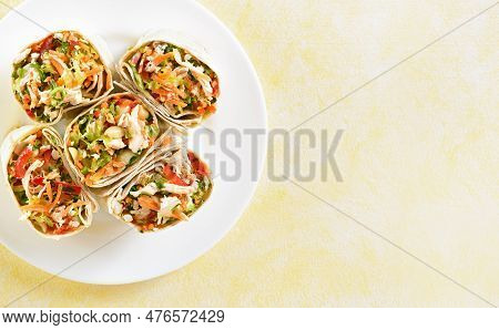 Close Up View Of Tortilla Wraps With Chicken And Fresh Vegetables On Plate Over Yellow Background Wi