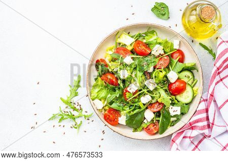 Spring Salad In Craft Plate. Spinach, Arugula, Tomatoes And Feta With Olive Oil. Top View On White.