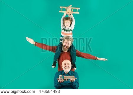 Three Different Generations Ages Grandfather Father And Child Son Playing With Toy Plane In Studio. 