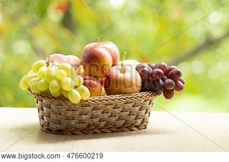 Fresh Ripe Apples, Peaches, Green And Blue Grapes In Basket. Healthy Food On Table On Defocus Autumn