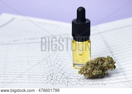 A Glass Bottle With Yellow Cbd Oil Next To A Dry Bud Of Medical Marijuana Against The Backdrop Of El