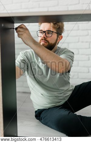 Young Attractive Man Assembles Furniture - Handwerker And Interior Objects Concept