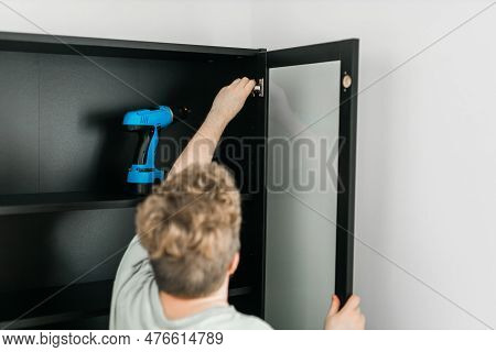 Young Attractive Man Assembles Furniture - Handwerker And Interior Objects Concept