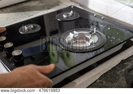 A Man Installs A Built-in Glass-ceramic Gas Stove On A Kitchen Countertop.