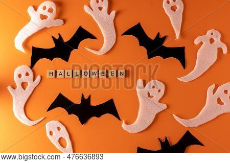 White Ghosts And Bat Craft For Halloween Party. Wrapping Paper Ghost On Orange Background Top View. 