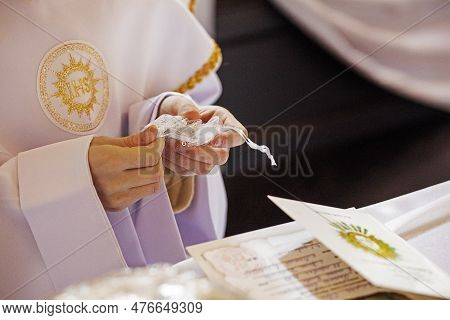 Children's Hands Untie The Bag, Which Contains The Rosary For The First Communion. Catahese Traditio