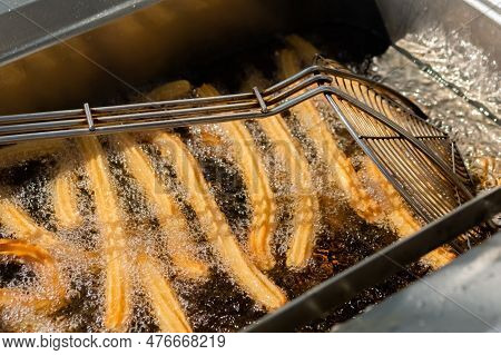 Process Of Cooking Homemade Crunchy Yellow Churros In Boiling Oil At Summer Outdoor Food Market - Cl