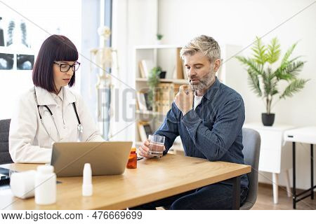 Caucasian Patient And Doctor Discussing Diagnosis With Further Treatment And Making Medical Record O