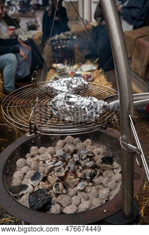 Potato In Alumnium Foil Baked On Charcoal Barbecue Grill Outdoor