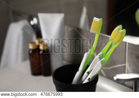 Light Green Toothbrushes In Black Toothbrush Holder Indoors