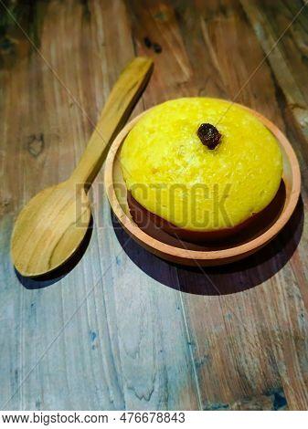 A Mud Cake With Raisin Topping On A Bowl And A Wooden Spoon Beside It