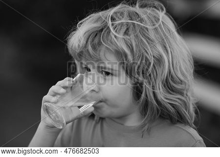 Child Drinking Water Outdoor In Park. Kid Drinking. Close Up Portrait Of Boy Drink Water From Glass 