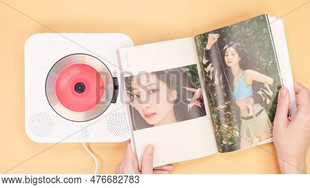 Hands Holding Twice Between 1 And 2 Mini Album Photobook On Yellow. Music Cd Player. South Korean Gi