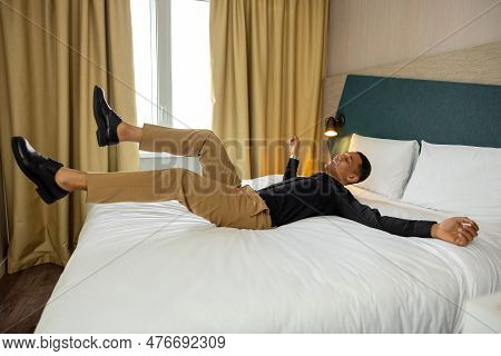 Young Man Lying On Bed In The Hotel Rooma And Feeling Relaxed