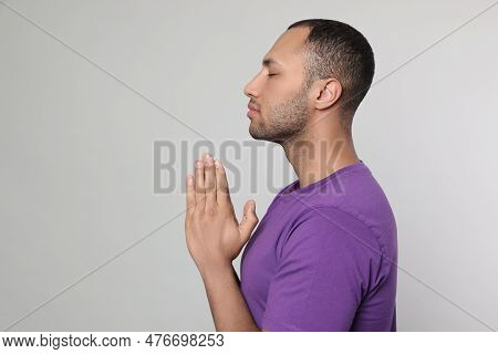 African American Man With Clasped Hands Praying To God On Light Grey Background. Space For Text
