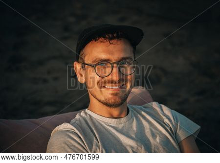 Young 32 Years Old Caucasian Man Traveler Tourist With Basecap On Sandy Beach On Sand Dune. Close-up