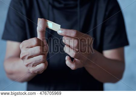 Man Placing Bandage Or Adhesive Plaster On His Thumb Finger. Plaster On The Wound