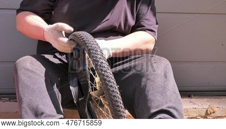 A Man Wearing Work Gloves Inserts A New Tube Into A Bicycle Wheel. A Man Repairs His Sons Bike. Repa