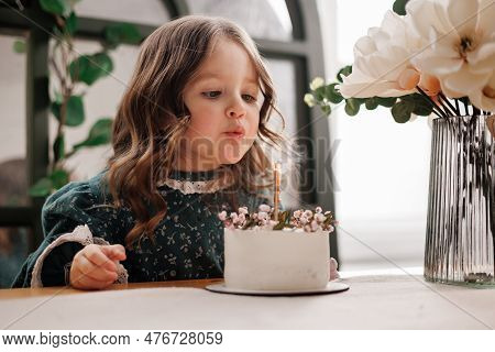 Child Birthday Party. Adorable Little Girl Sits By The Table With Birthday Cake Decorated Flowers An