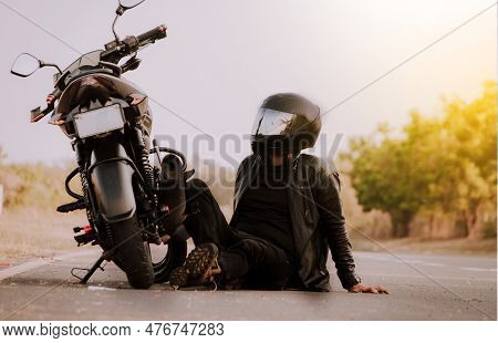 Motorcyclist Sitting Next To His Motorcycle. Motorcyclist Sitting And Leaning On His Motorcycle On T