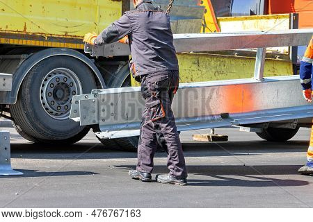 A Road Service Worker Installs A Delimiting Metal Barrier In The Middle Of The Carriageway.