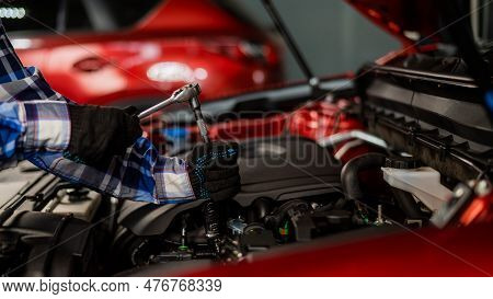 Female Auto Mechanic Unscrewing A Nut To Replace A Car Spark Plug.