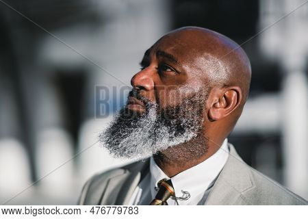 A Close-up Portrait Of The Profile Of A Charming Black Man With A Long Greying Beard, Dressed In A G