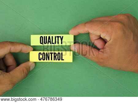 Hand Holding Colored Paper With The Word Quality Control. The Concept Of Quality Control Or Producti