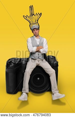 Portrait Of Uninspired Unhappy Male Photographer With Broken Lightbulb Idea, On A Yellow Background