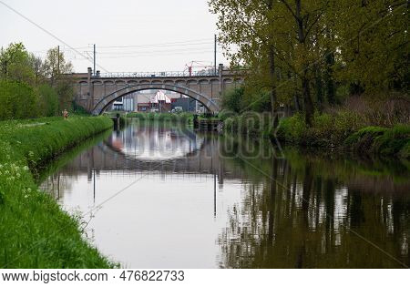 Dendermonde, East Flanders, Belgium - May 1, 2023 - Old Bowed Bridge Reflecting In The Water Of The 