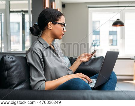 Young Female Entrepreneur In Thought Sitting On The Floor In The Kitchen With A Laptop On Her Legs