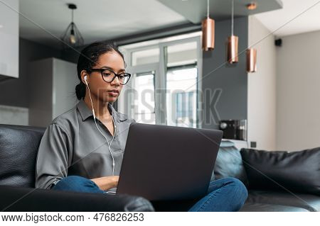 Young Female Entrepreneur In Thought Sitting On The Floor In The Kitchen With A Laptop On Her Legs