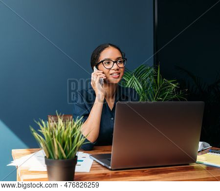 Young Female Entrepreneur In Thought Sitting On The Floor In The Kitchen With A Laptop On Her Legs