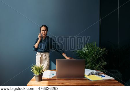 Young Female Entrepreneur In Thought Sitting On The Floor In The Kitchen With A Laptop On Her Legs