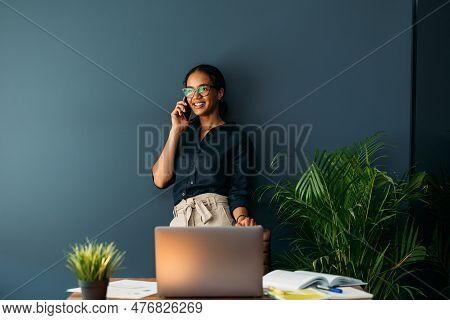 Young Female Entrepreneur In Thought Sitting On The Floor In The Kitchen With A Laptop On Her Legs