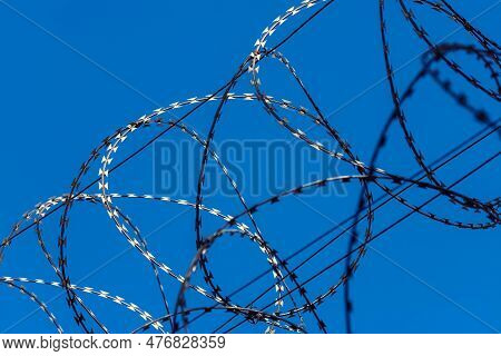 Closeup Of A Razor Wire Against The Blue Sky As A Restriction Concept. Background With Copy Space