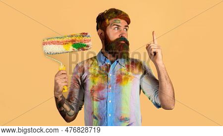 Painter Man With Paint Roller Pointing Finger Up. Professional Painter, Decorator, Builder Worker Wi