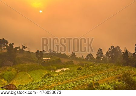 Hazy Sunset Over Green Village On The Mountain Slopes Of Merbabu, Central Java, Indonesia.