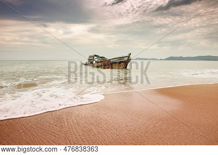 Seascape Of Wreck Boat On Sand Beach With Cloudy Sky In Tropical Region Season